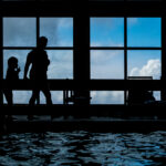 Color silhouette Photo of boy at pool using sign language to talk yo mom