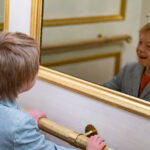 Color photograph of boy laughing while looking at himself in an elevator mirror at Capital Hotel in Little Rock, Arkansas.
