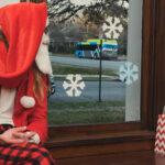 color photograph of santa claus sitting on a bench and looking out the window at a bus