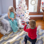 color photograph of boy with camera on one knee taking a picture of a drag queen at a holiday drag reading show for kids in Little Rock Arkansas
