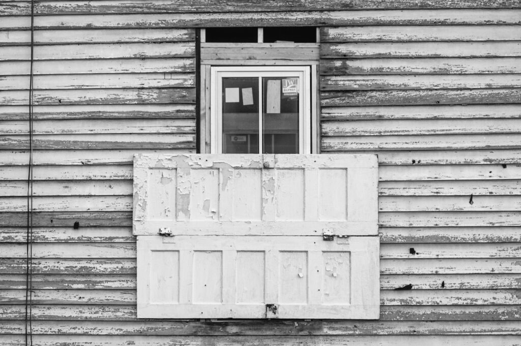 Black and white photograph of old wooden doors covering new windows on house restoration in Dunbar neighborhood in Little Rock, Arkansas