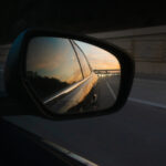 color photograph of sunset over little rock arkansas as seen in rear view mirror of mazda driving down interstate 630